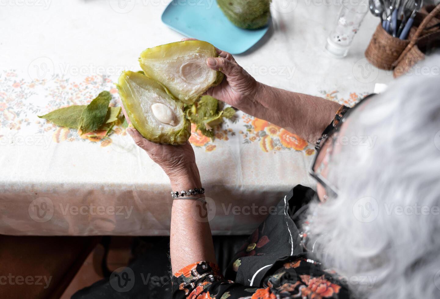 A senior mexican woman is showing the inside of a fresh cooked chayote after peeling it photo