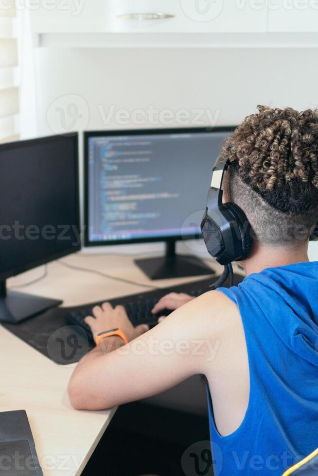 Computer programmer sitting at desk and typing on computer keyboard while creating code while working at home. photo