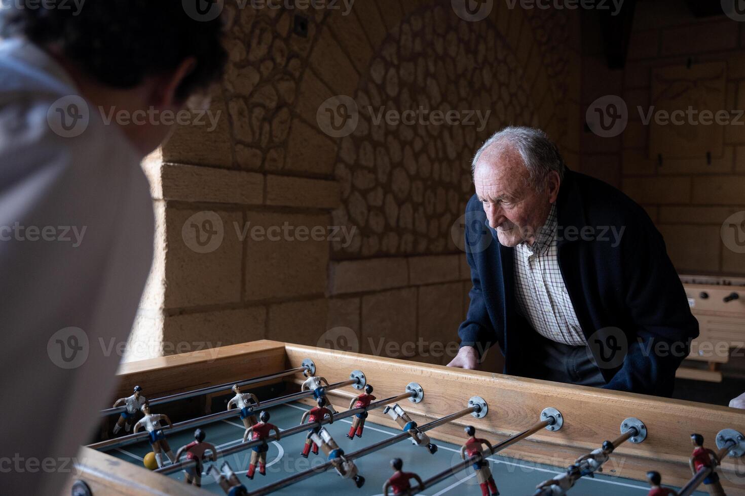 An old man is playing table football with his family photo