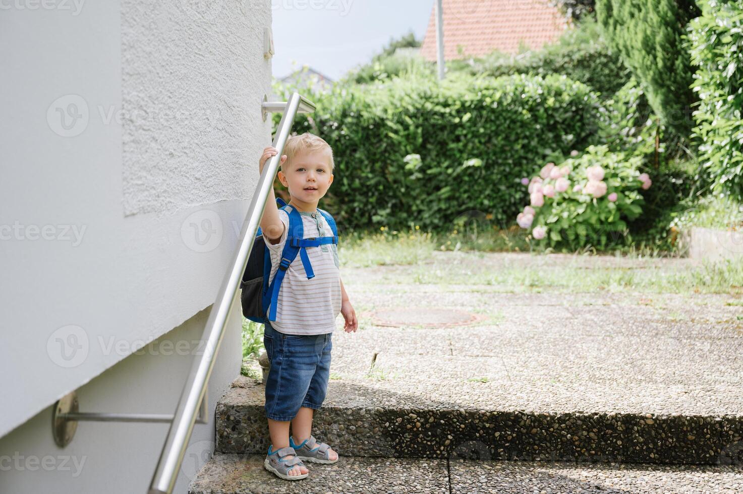 Happy child with backpack standing outside photo