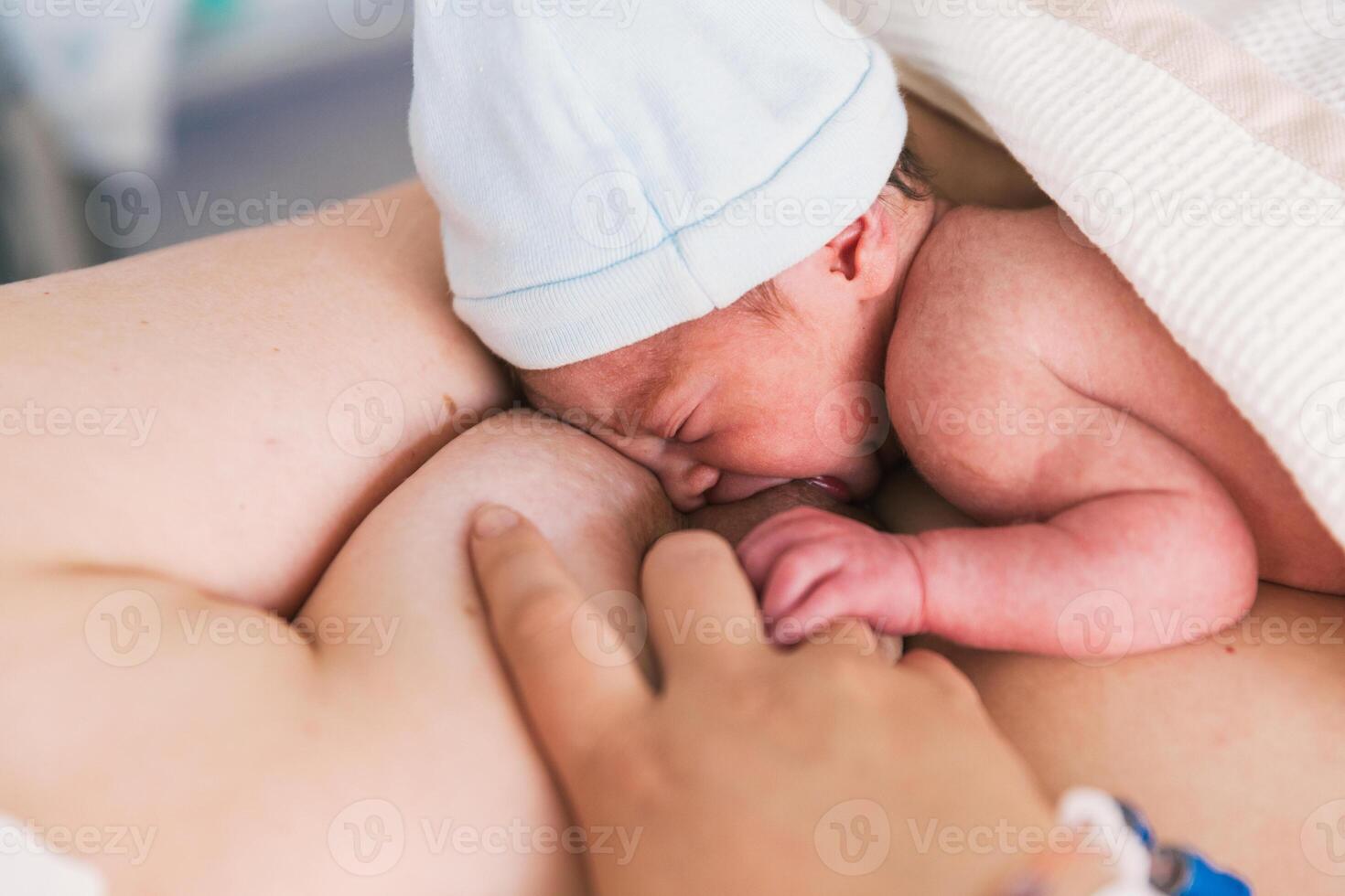 Close-up view of a woman breastfeeding her newborn baby in the hospital room after birth. photo