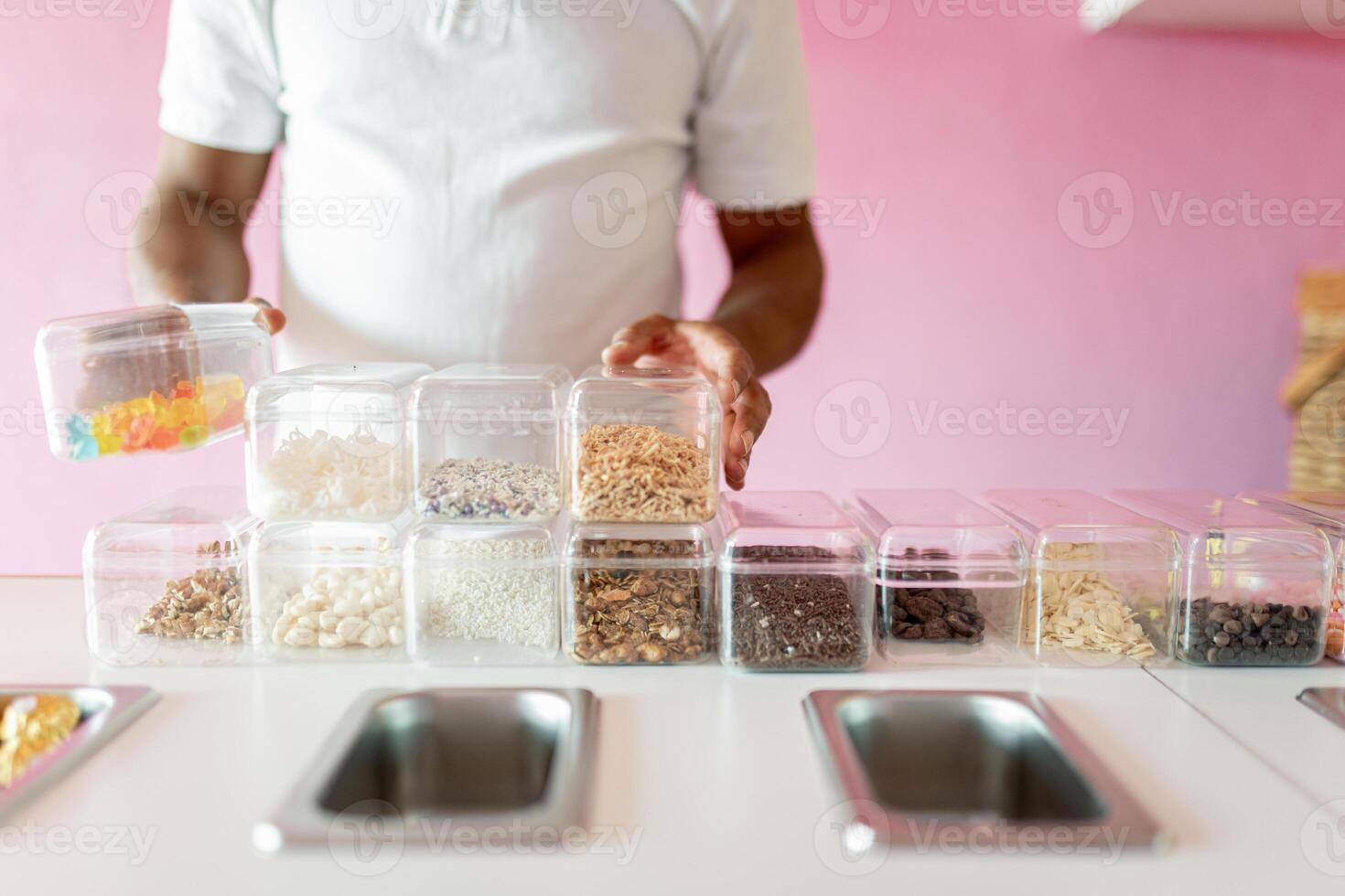 An ice-cream parlor worker is preparing all the toppings for the day on the counter photo