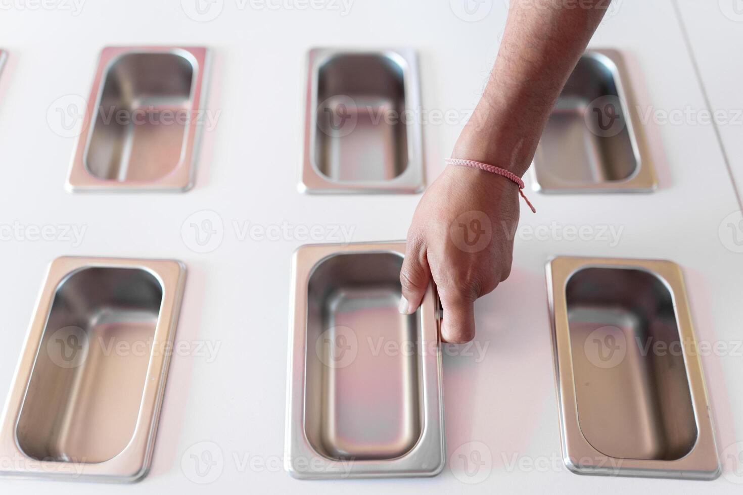A hand of an ice-cream parlor worker is placing a clean metal tray photo