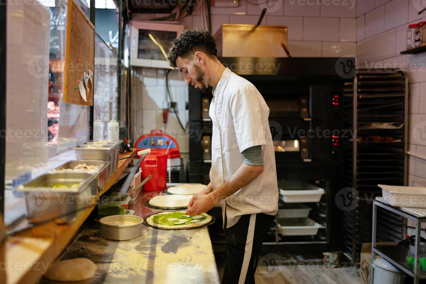 Pizza man adding zucchini to pizza photo