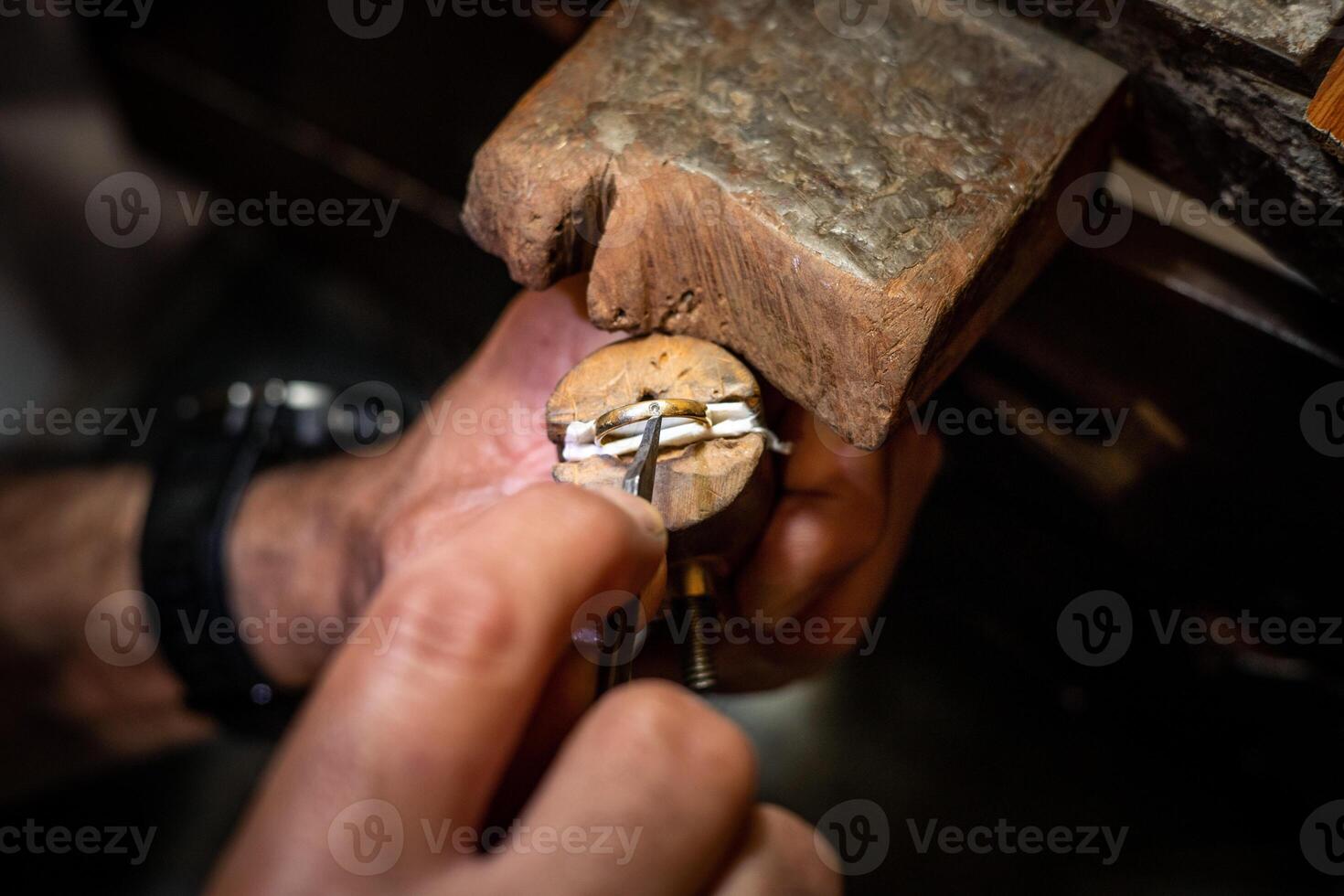 Jeweler hands setting a diamond into a ring with a burin in a jewelry workshop. Goldsmith working and creating a gold jewel. photo
