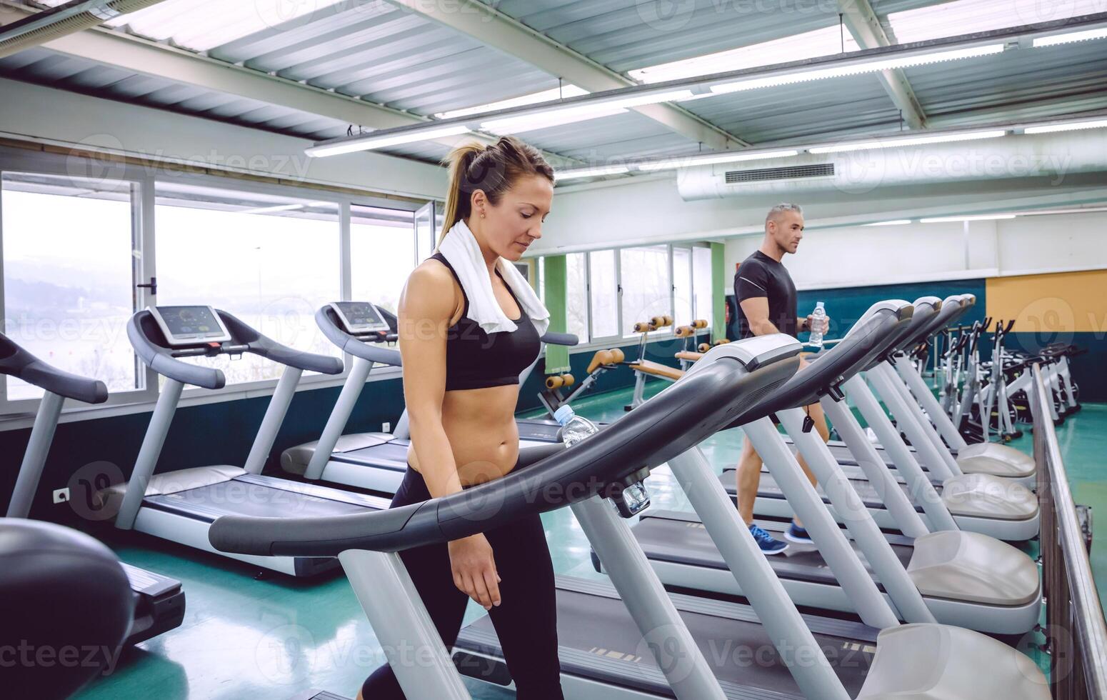 Fitness woman with towel training on a treadmill photo