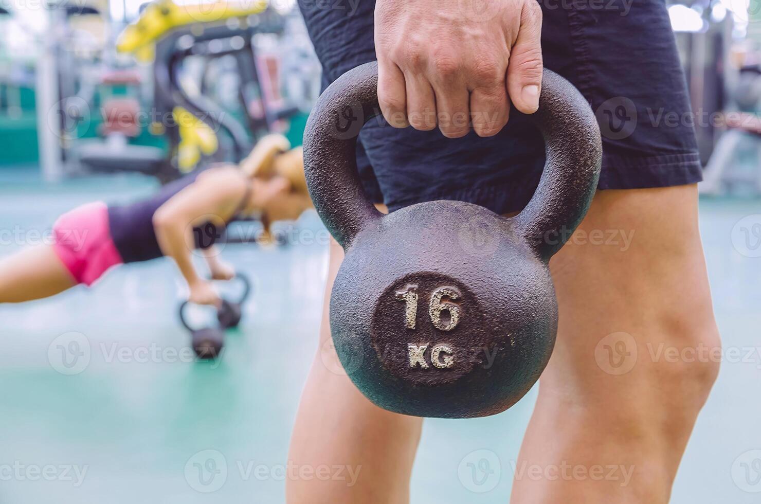 Man holding kettlebell and woman doing pushups in kettlebells photo