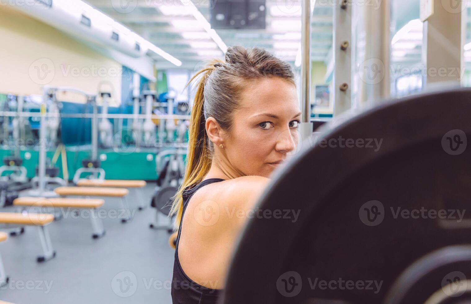 Woman resting after lifting barbell on muscular training photo