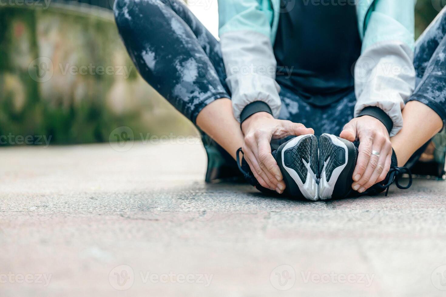 Woman runner relaxing sitting on the floor while holding her feet photo