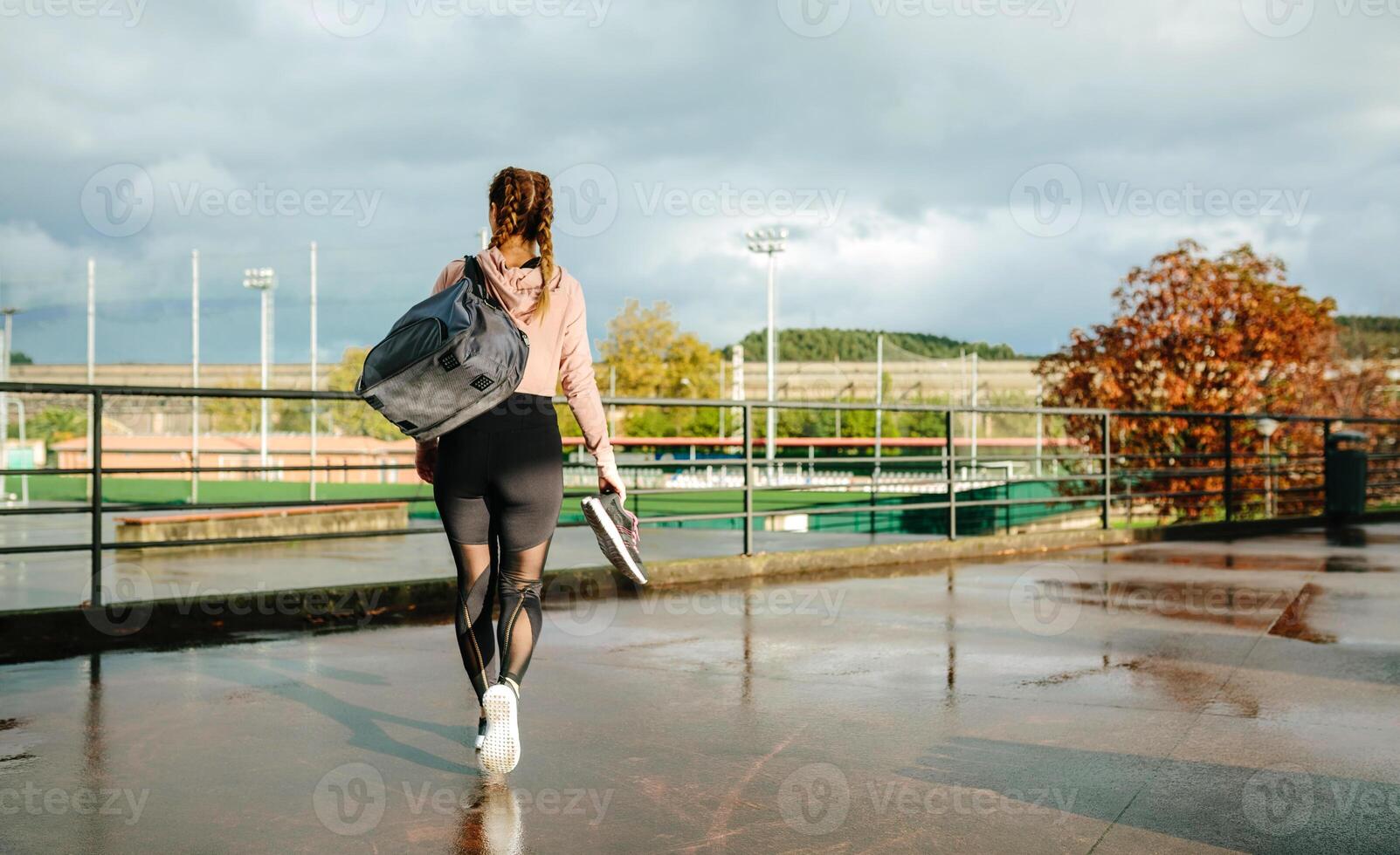 Sportswoman with gym bag and sports shoes walking to go to training photo