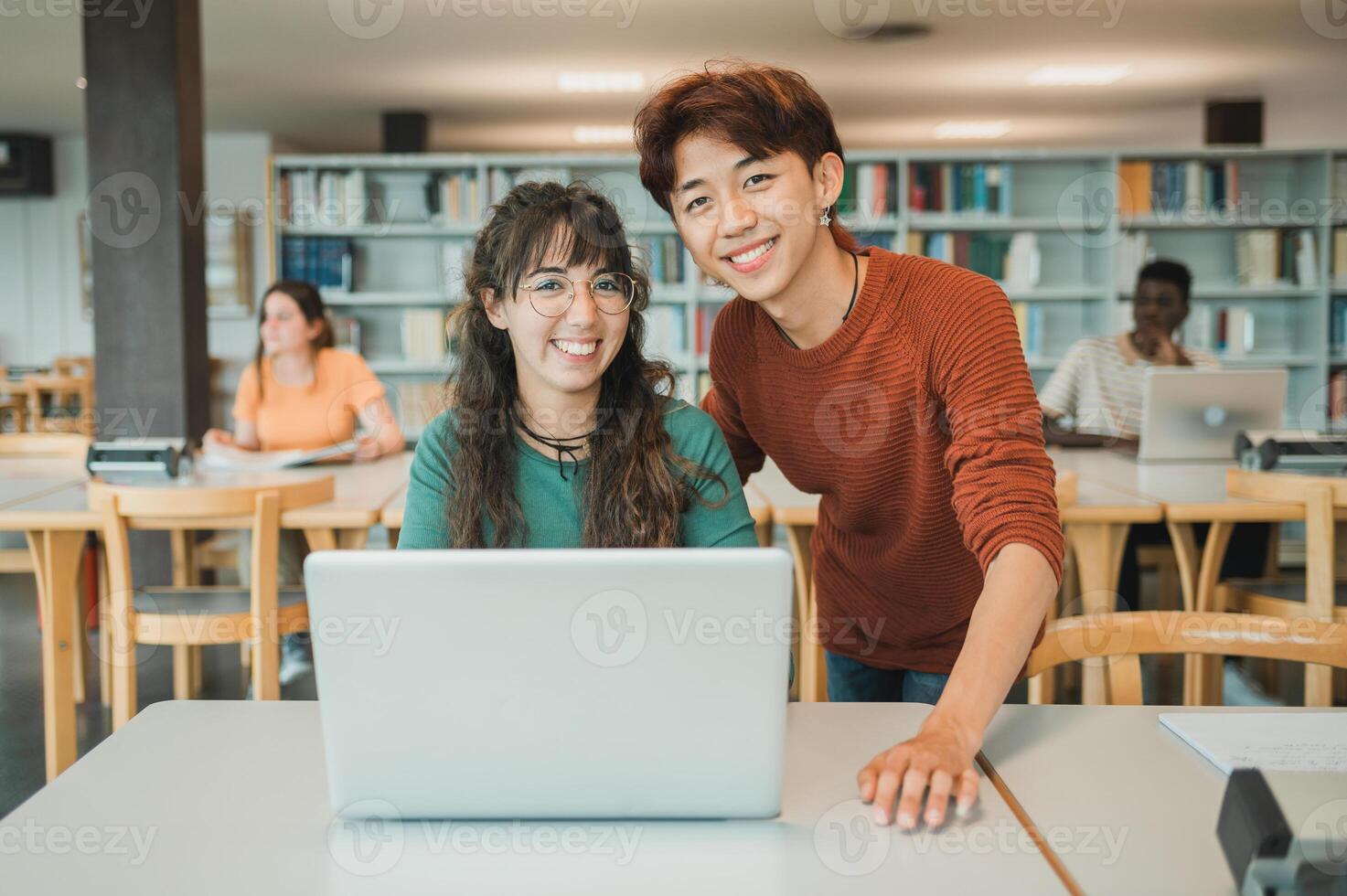 Multiracial teenagers using laptop during studies in library photo