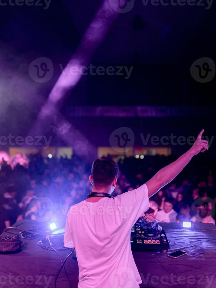 DJ raising hand while playing on stage in a club photo