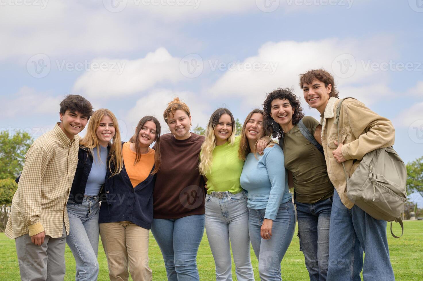 Happy multiethnic groupmates smiling and looking at camera in park photo