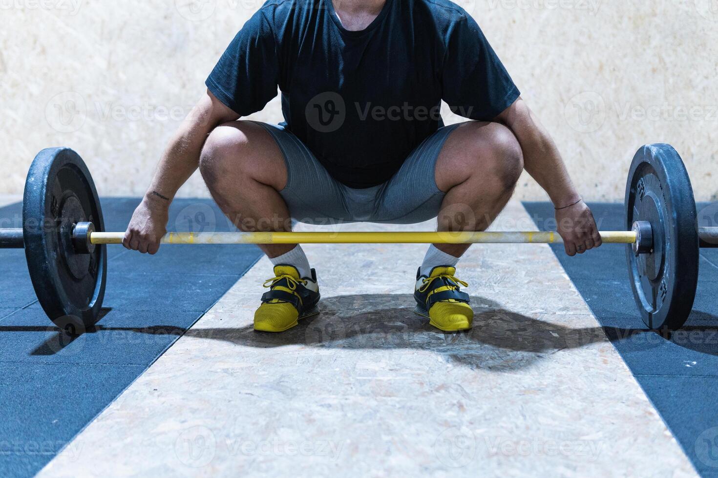 Unrecognizable sportsman lifting barbell in gym photo