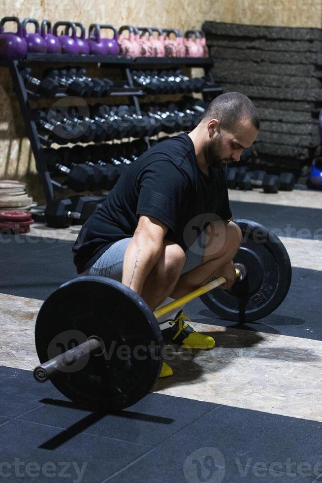 Muscular ethnic man preparing for lifting barbell photo