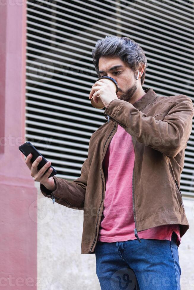 Man drinking takeaway coffee and browsing smartphone photo