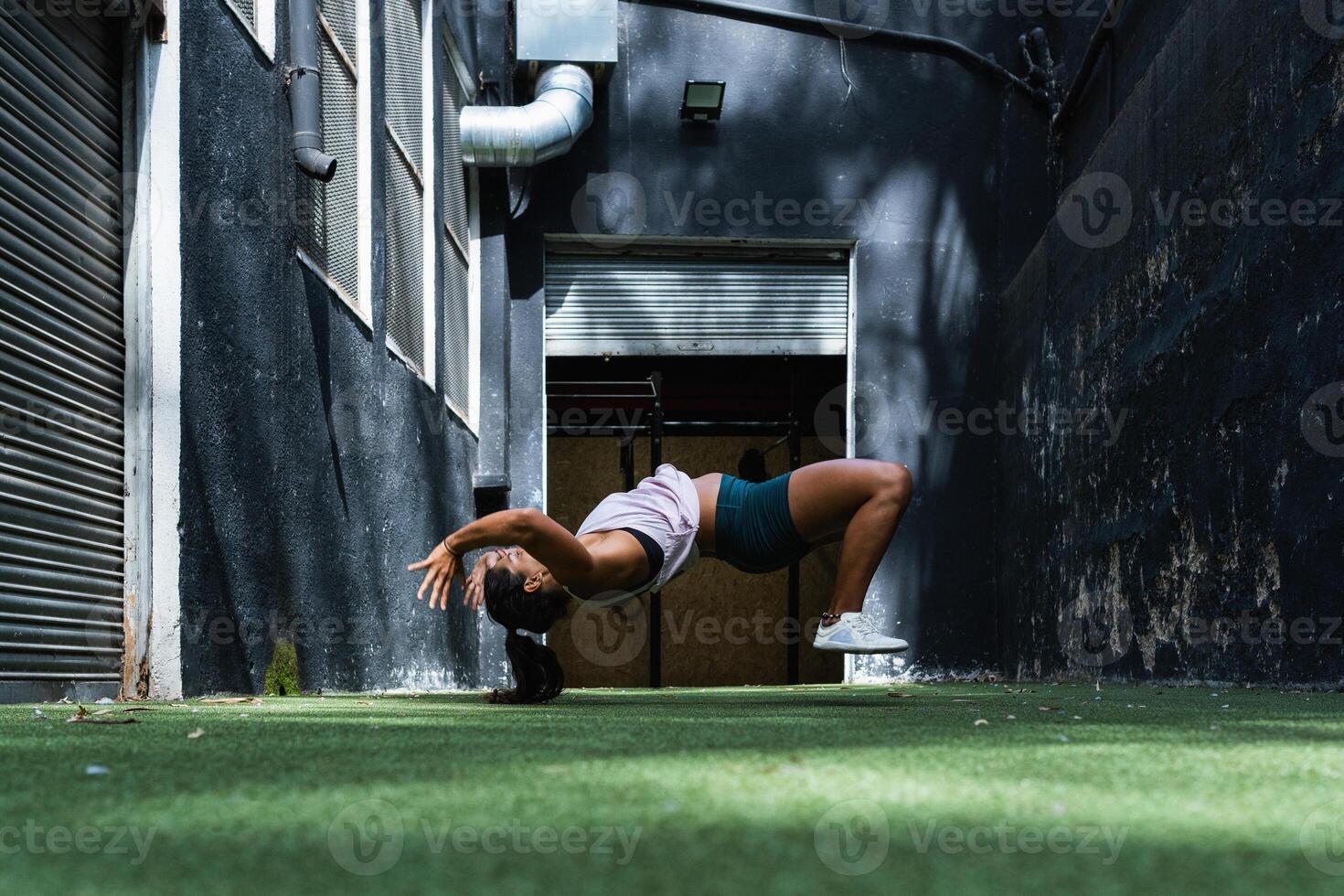 Fit ethnic woman doing somersault during training photo