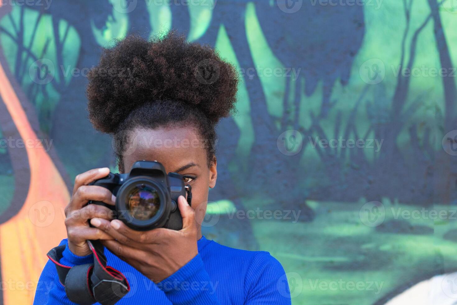 Black woman taking photo on camera in city