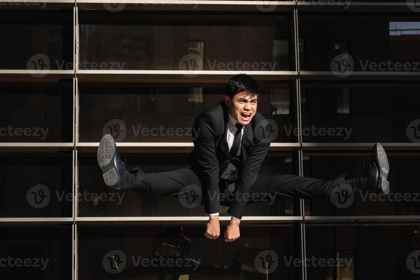 Businessman jumping in splits in city photo