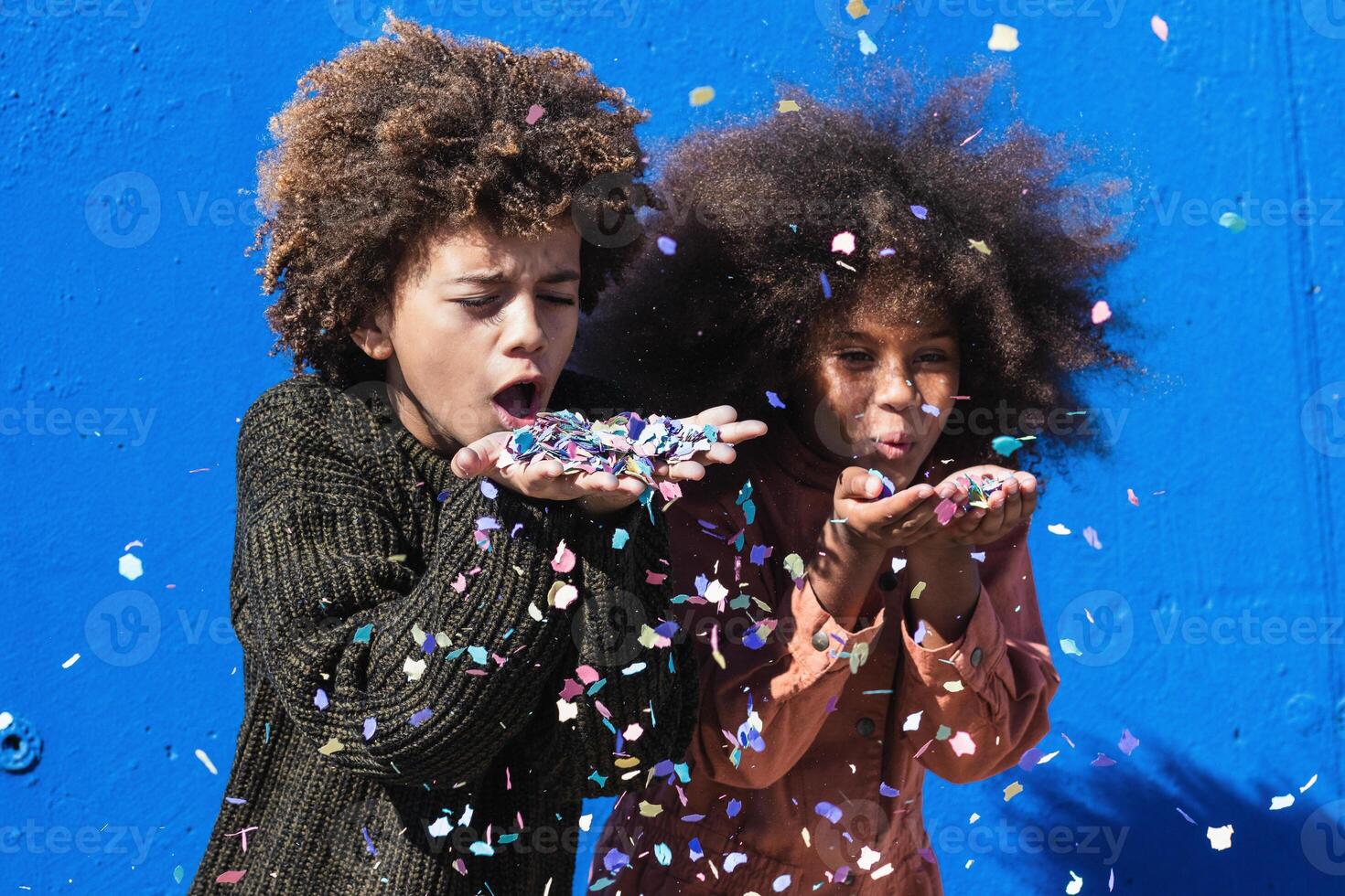 Cheerful black teenagers blowing confetti photo