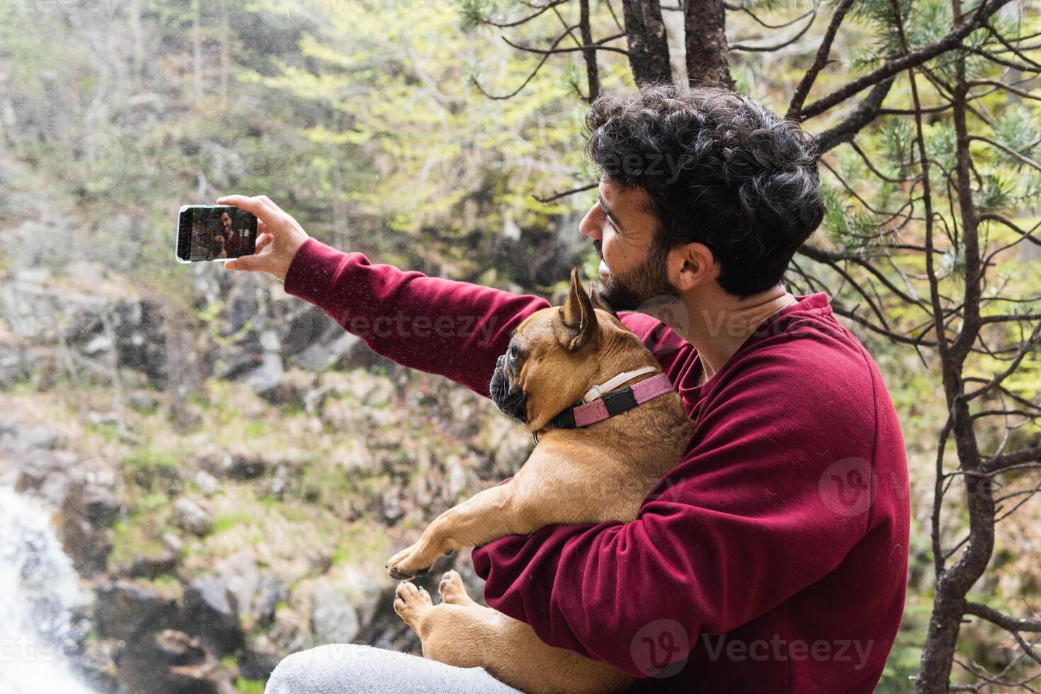 Smiling traveling man taking selfie with dog in forest photo