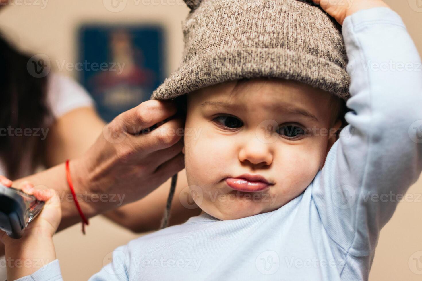 mother putting a hat on her baby at home photo