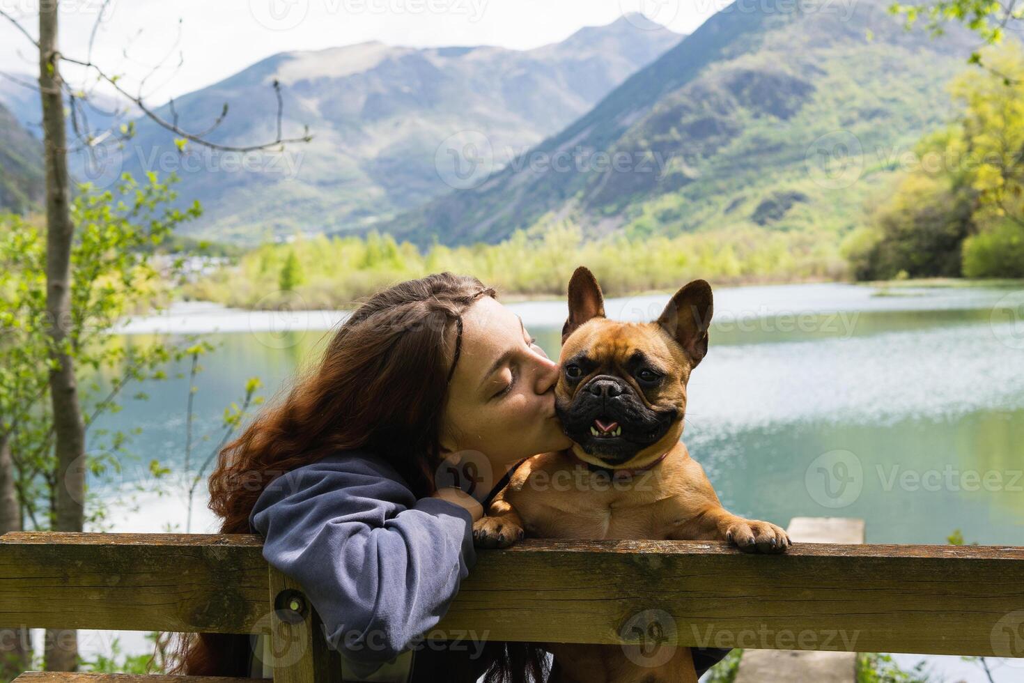 Female traveler kissing dog near lake in mountains photo