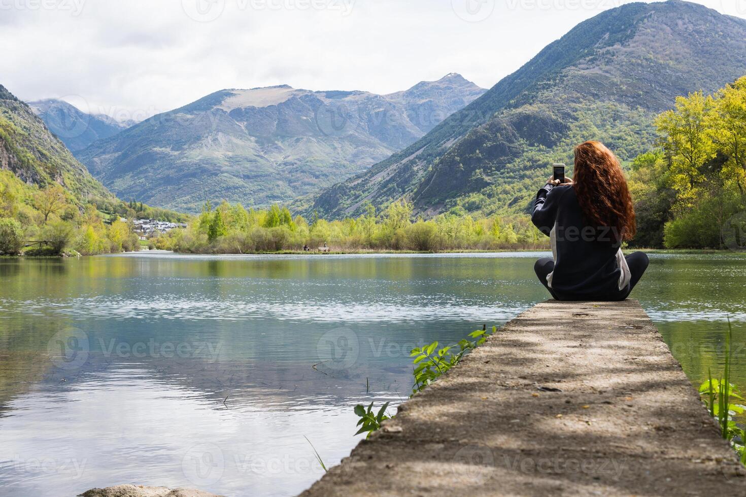 Anonymous traveler taking photo of lake in mountains