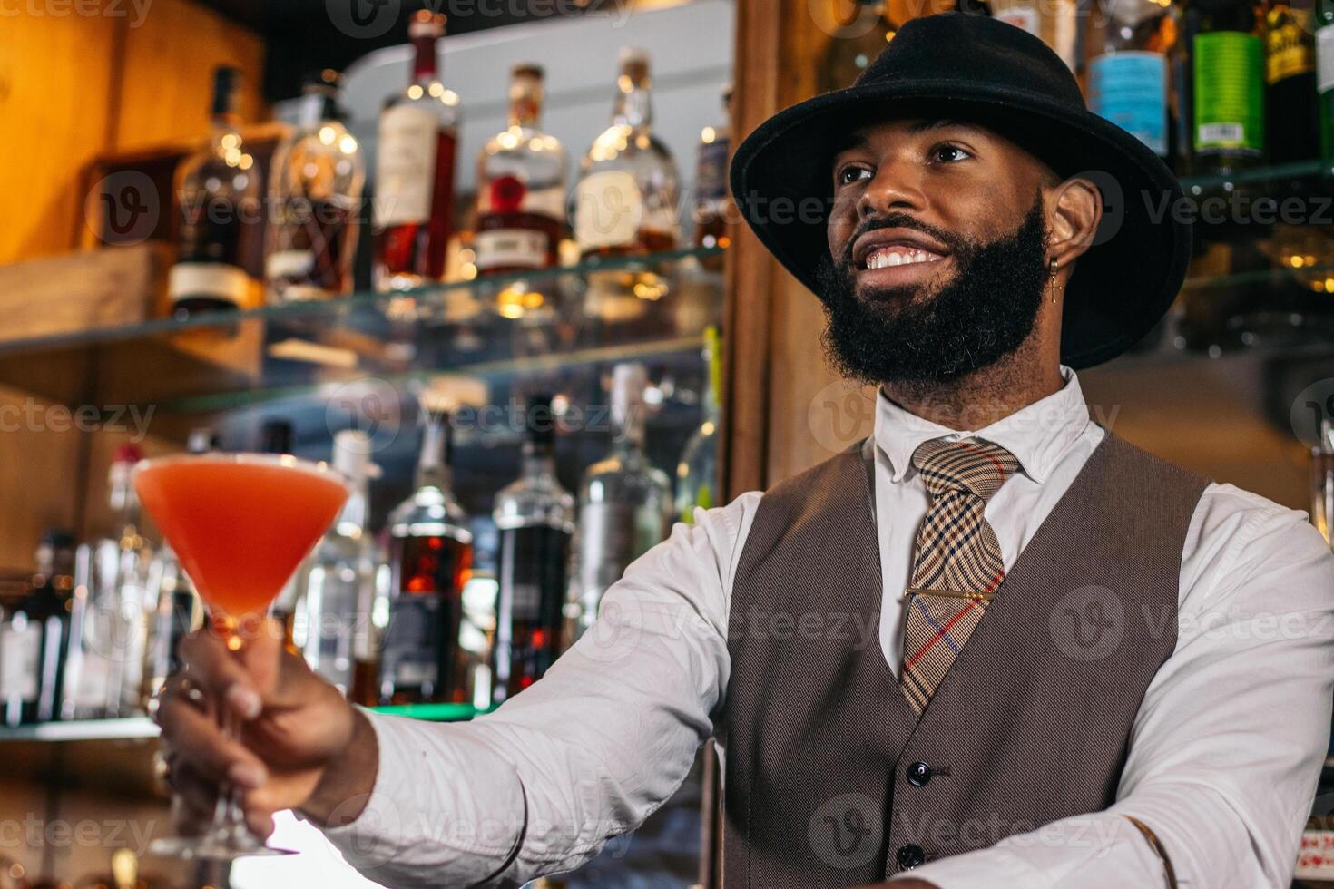 Stylish bartender offering a cocktail served in a martini glass in a traditional cocktail bar photo