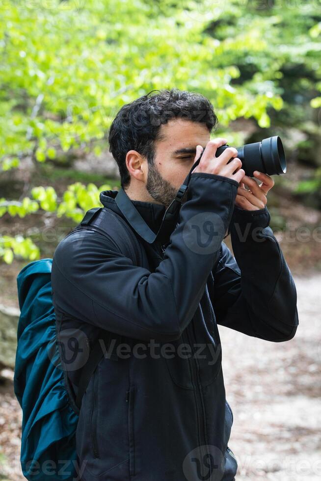 Traveling man taking photo on camera in woods