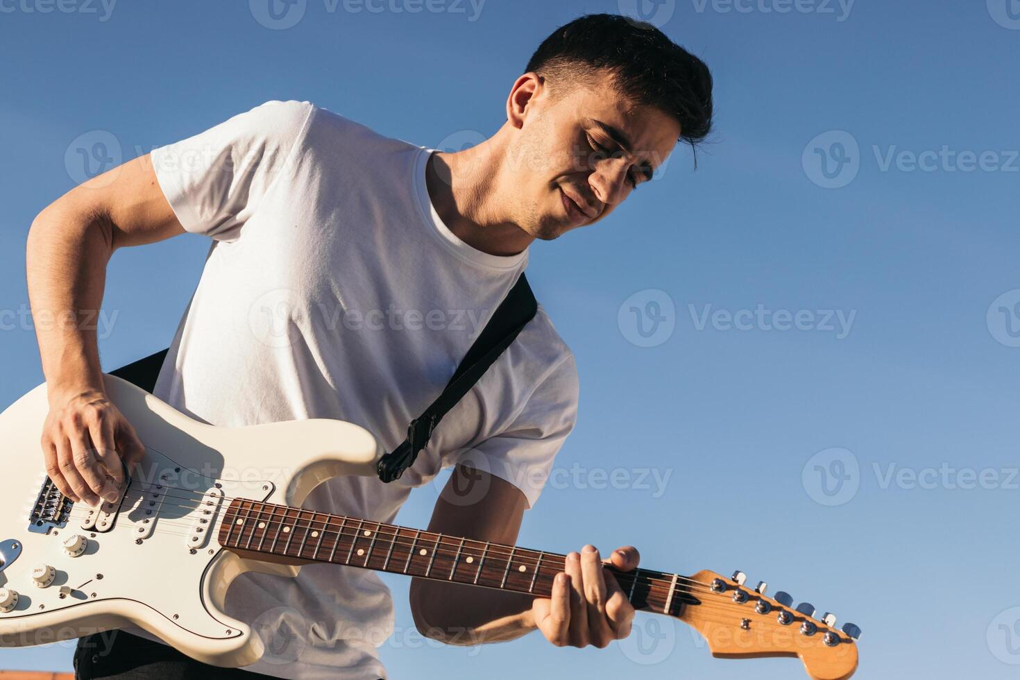 man playing electric guitar on a blue sky background photo