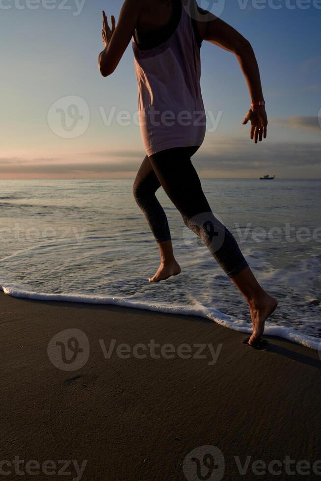 Anonymous woman running on seacoast at sundown time photo