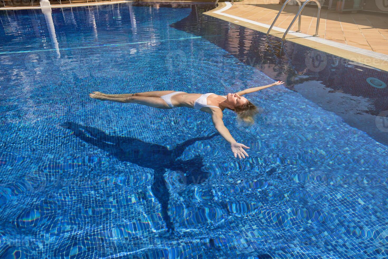 Female chilling while floating in pool water photo