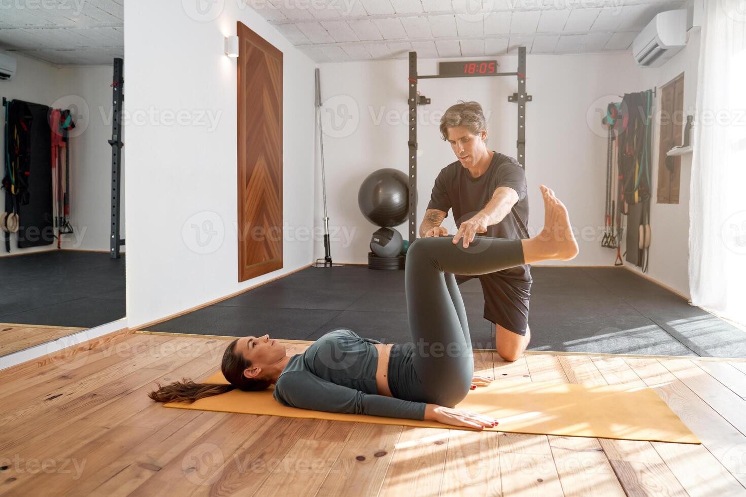 Lady doing yoga in gym with trainer photo