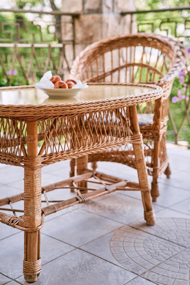 Plate with peaches stands on a wicker rattan table on the terrace photo