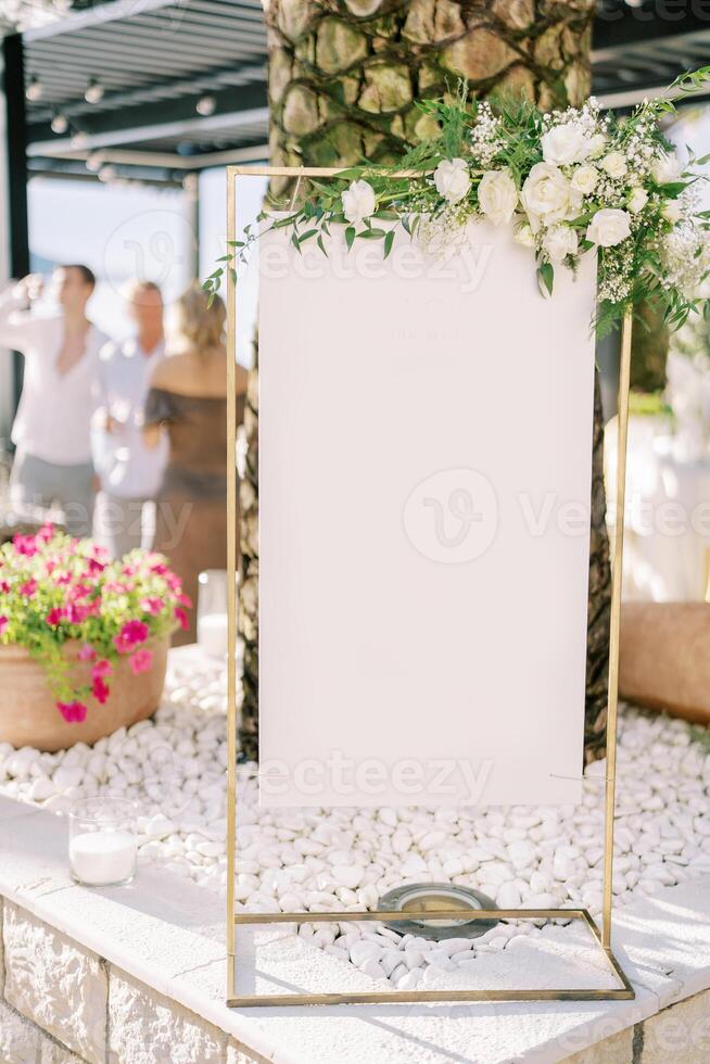 Blank sign on a counter near a palm tree on a restaurant terrace photo