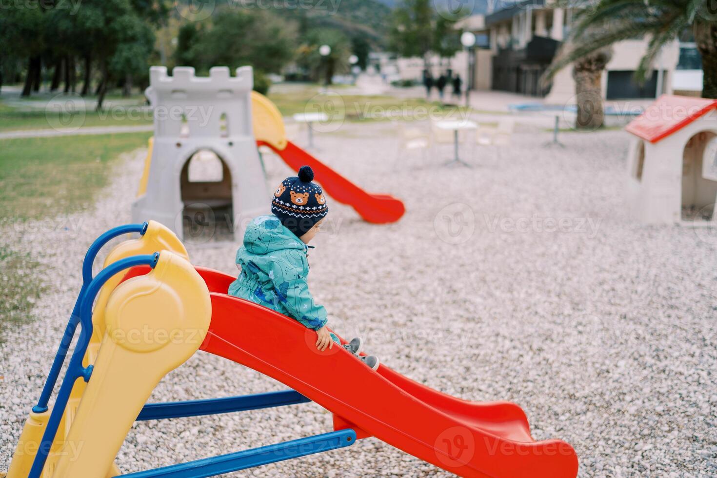 Little girl slides down a colorful slide in the playground. Side view photo