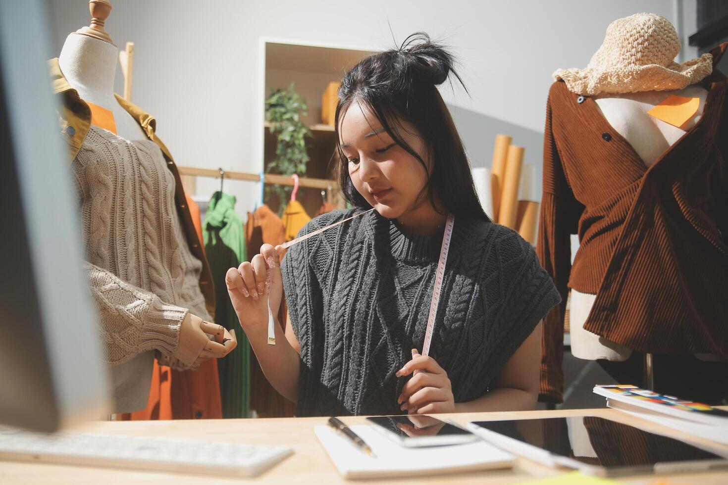 A woman is working on a computer in front of a dress photo