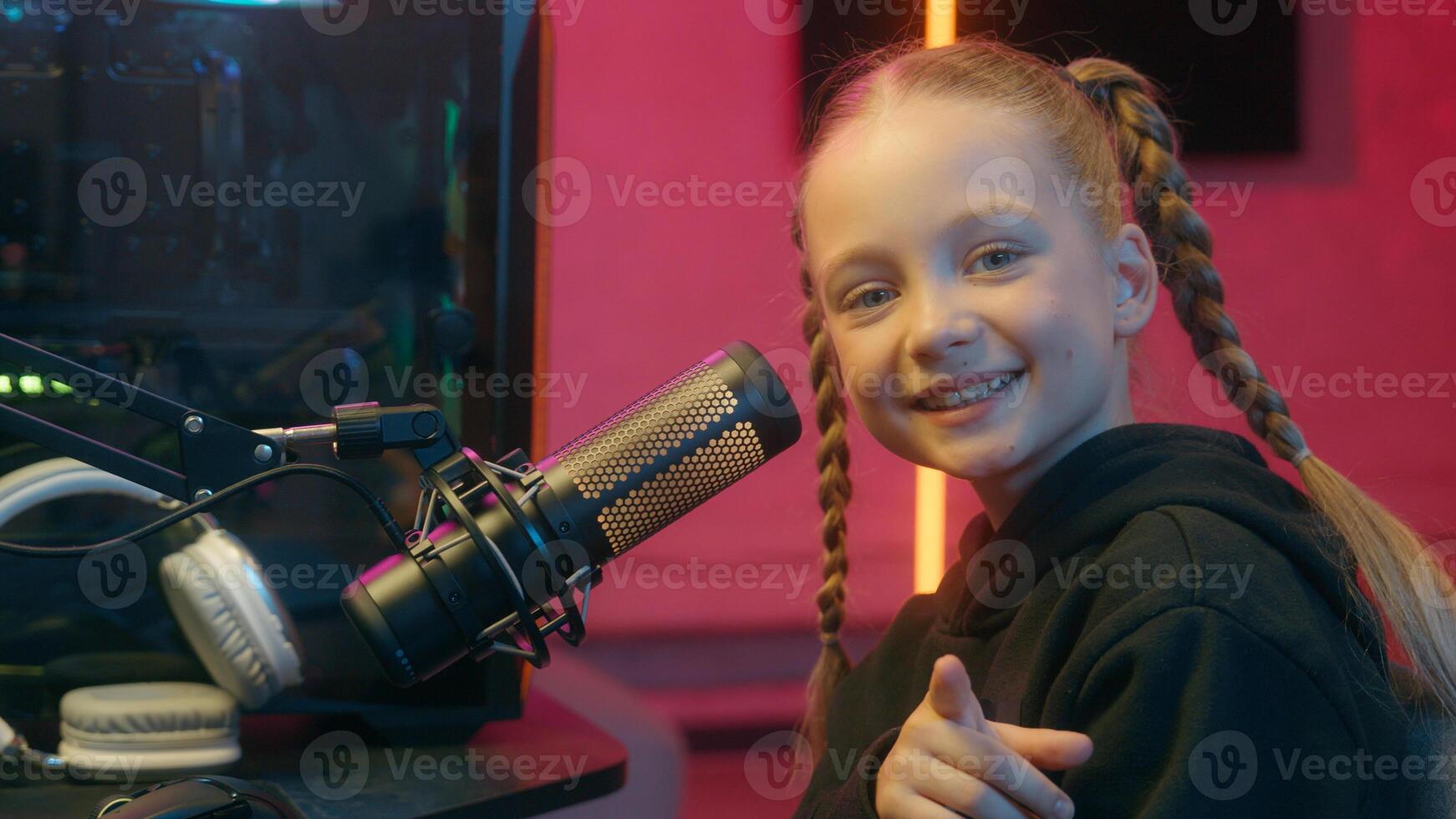 Caucasian little teen girl daughter child kid streamer gamer influencer gen z internet game computer addiction at night radio stream showing pointing index finger at camera smiling hey you look photo