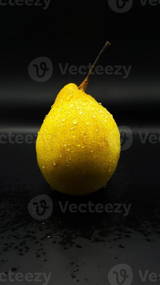 one wet pear on the table, a delicious yellow pear covered with water photo
