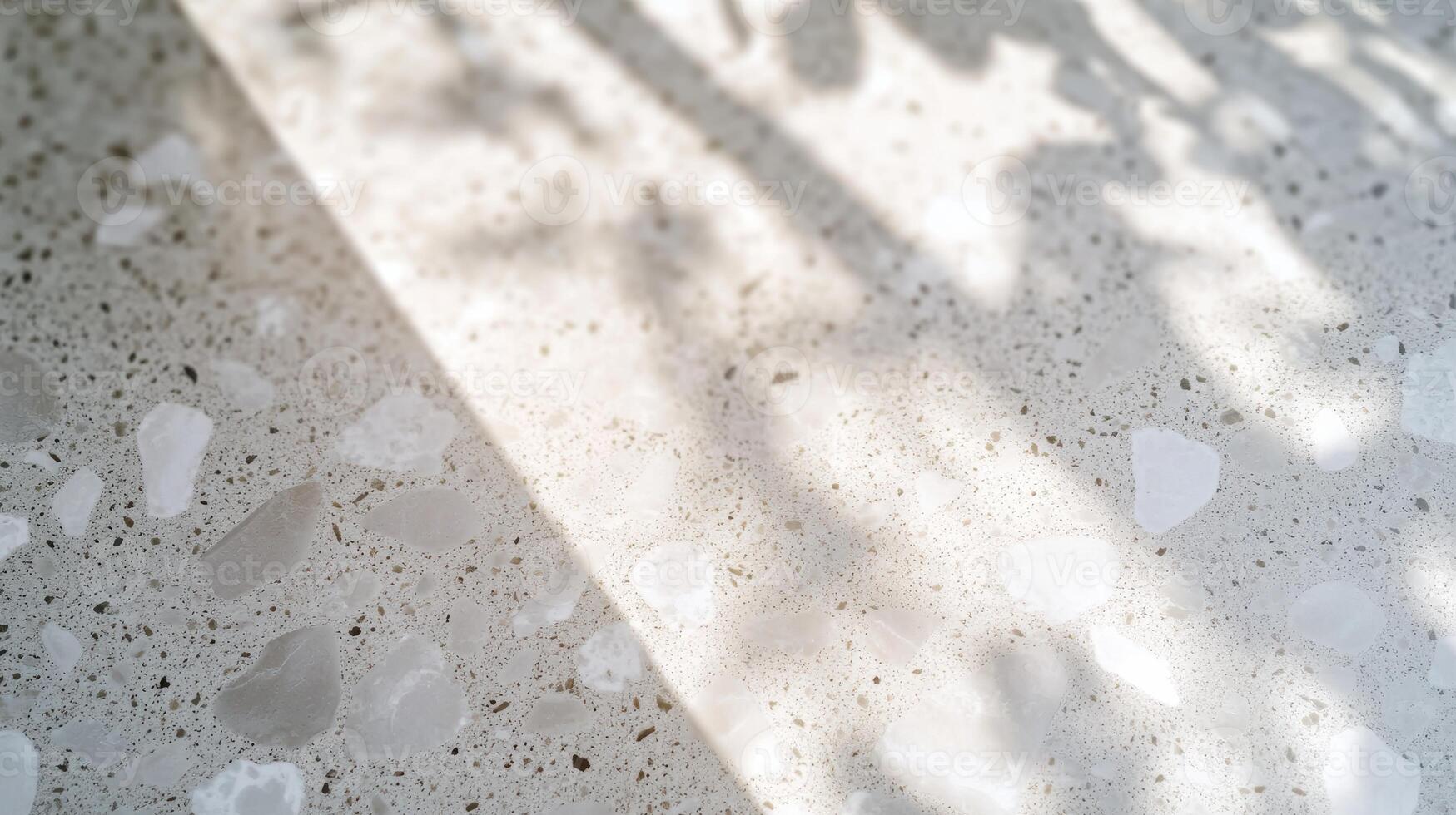 Sunlight casts shadows on textured terrazzo surface creating playful patterns photo