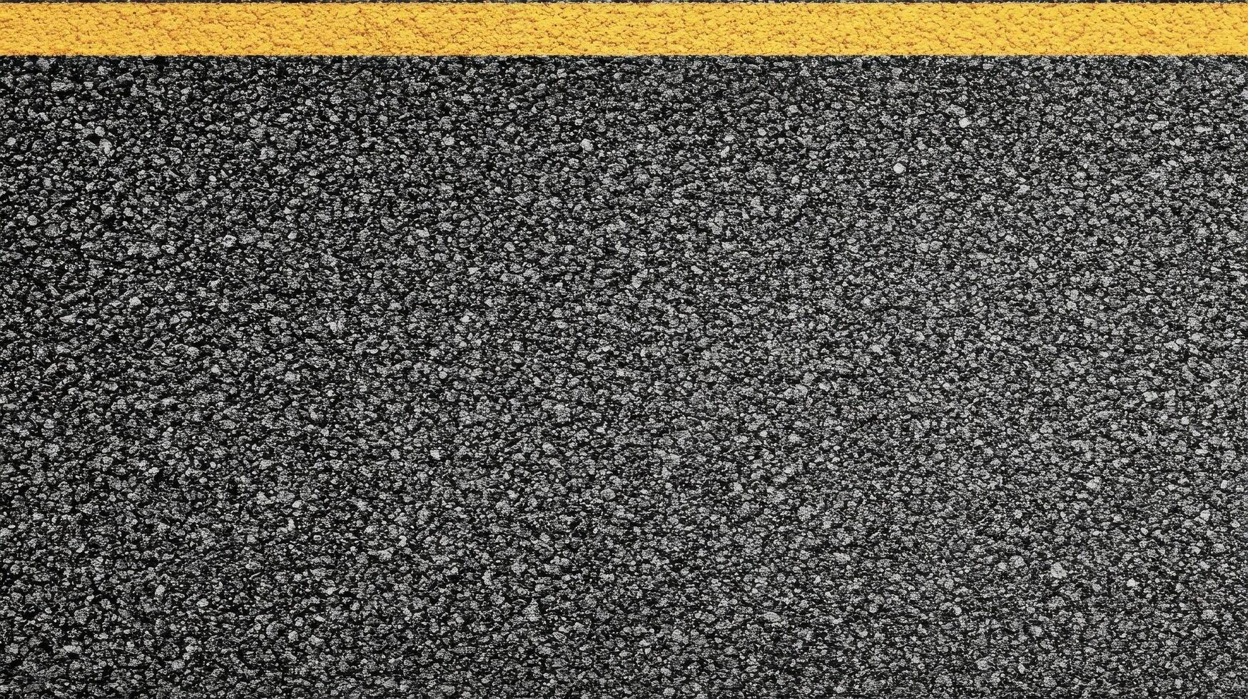 Close-up of textured asphalt road with yellow line dividing surface for transportation concept photo