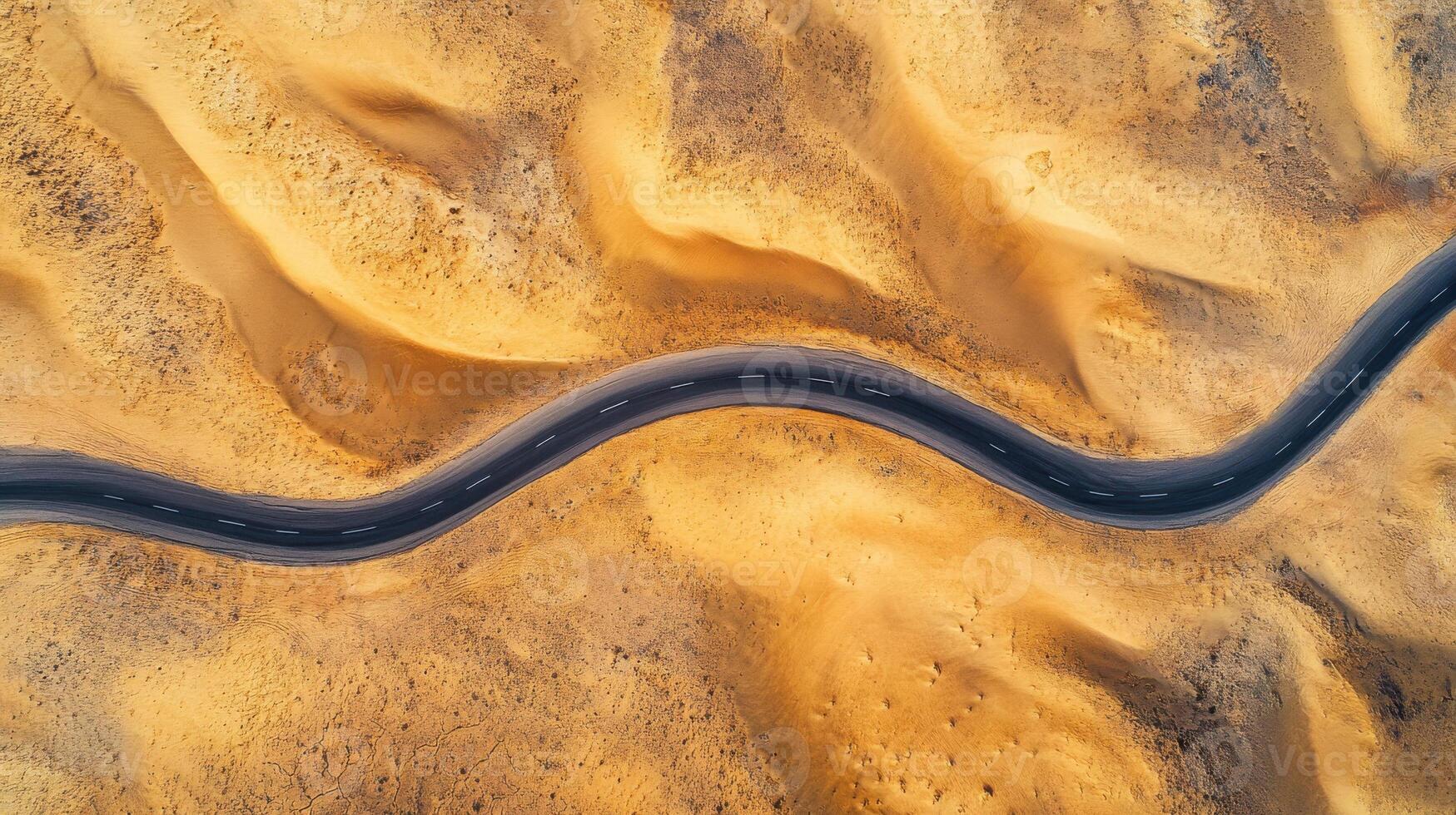 Aerial view of winding road through barren desert landscape captured in daylight photo