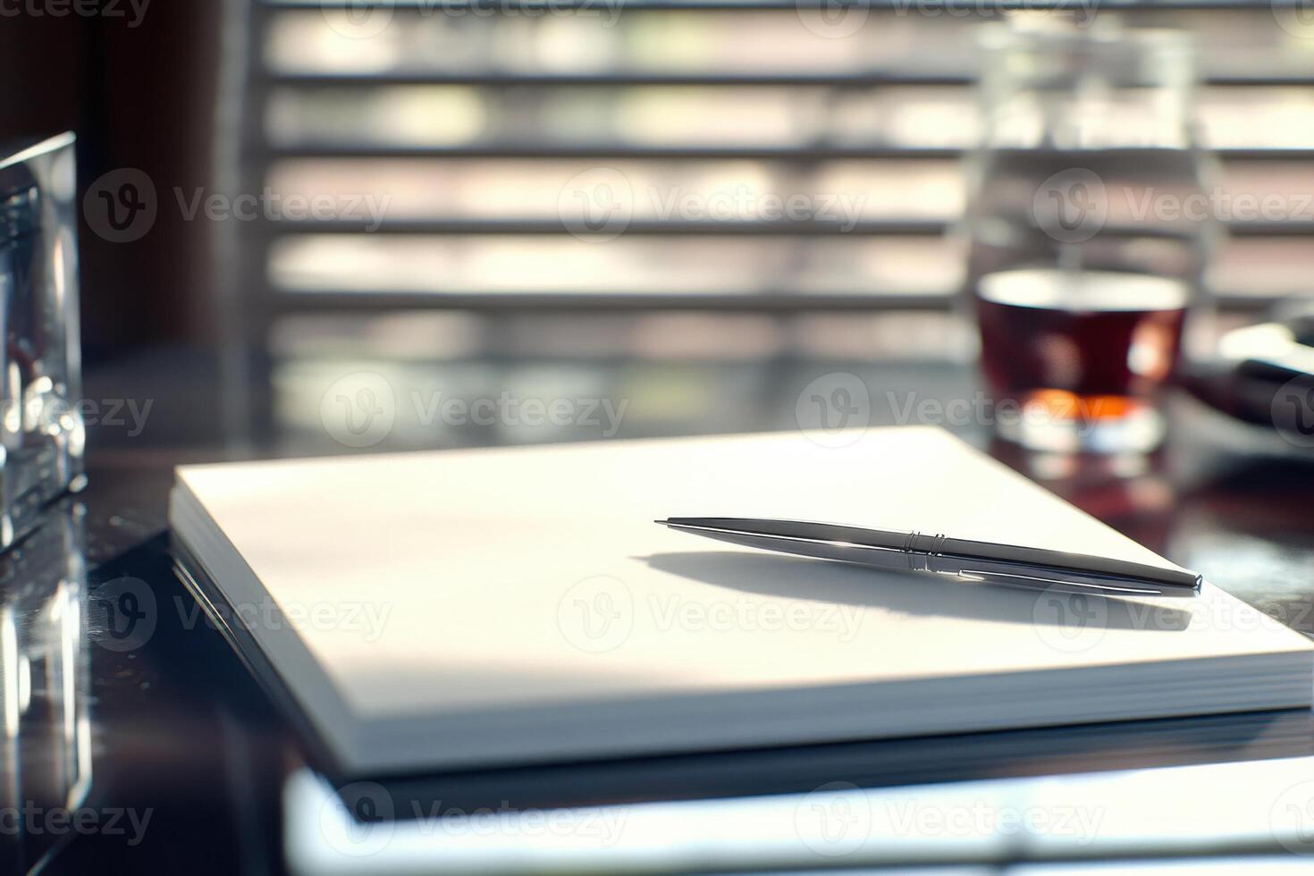 Pen resting on a blank notepad on a desk by a window with soft natural light photo