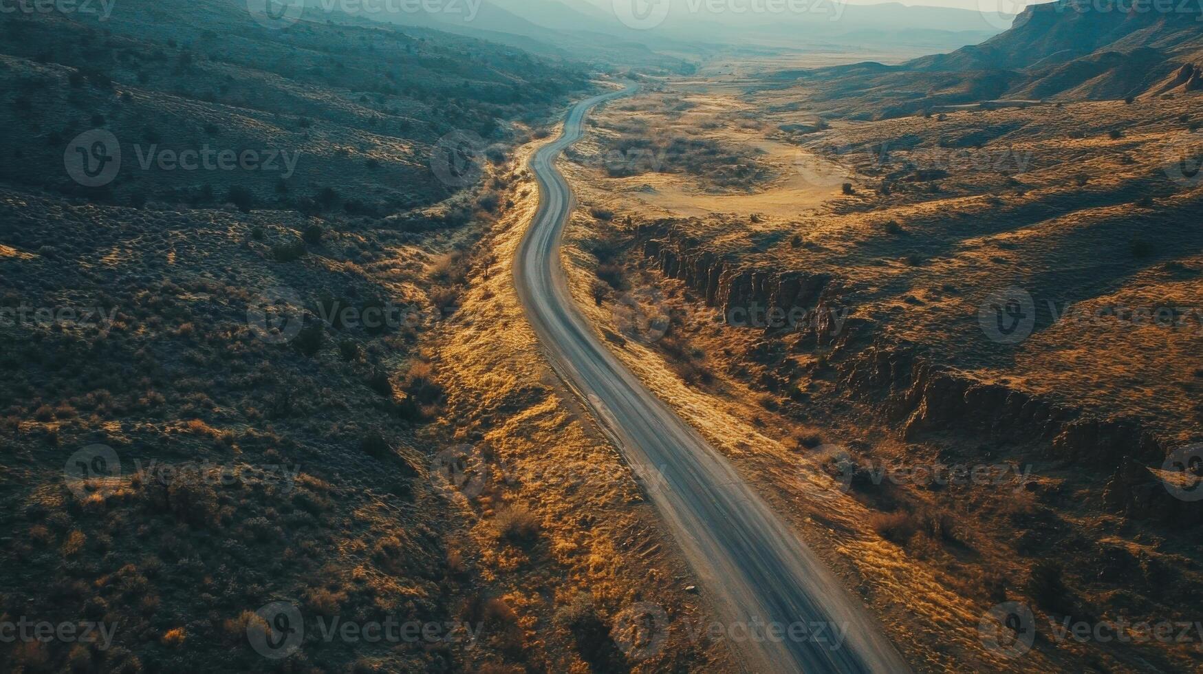 Winding rural road through arid landscape in golden hour light with mountain background photo