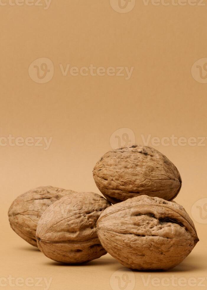 Stack of walnut fruits on brown background, close up photo