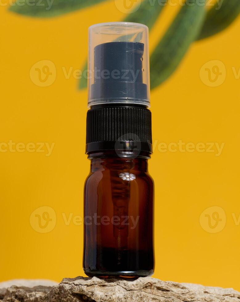 Brown glass bottle with dispenser stands on stone photo