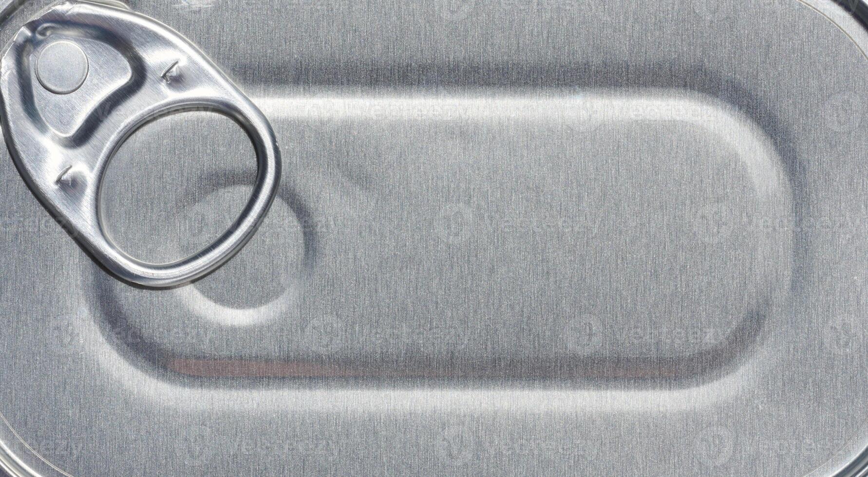 Gray aluminum tin can lid with key, top view. Full frame photo
