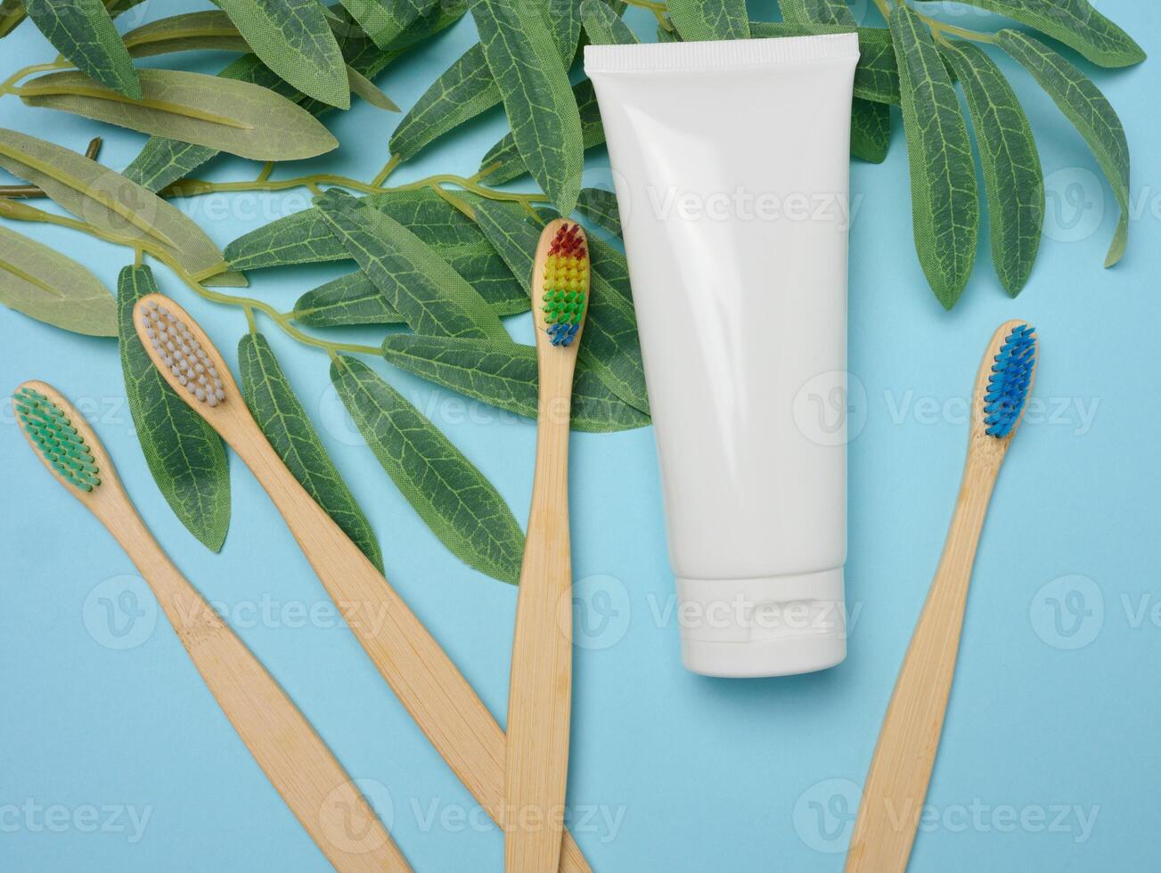 White plastic tube and bamboo toothbrush on blue background photo