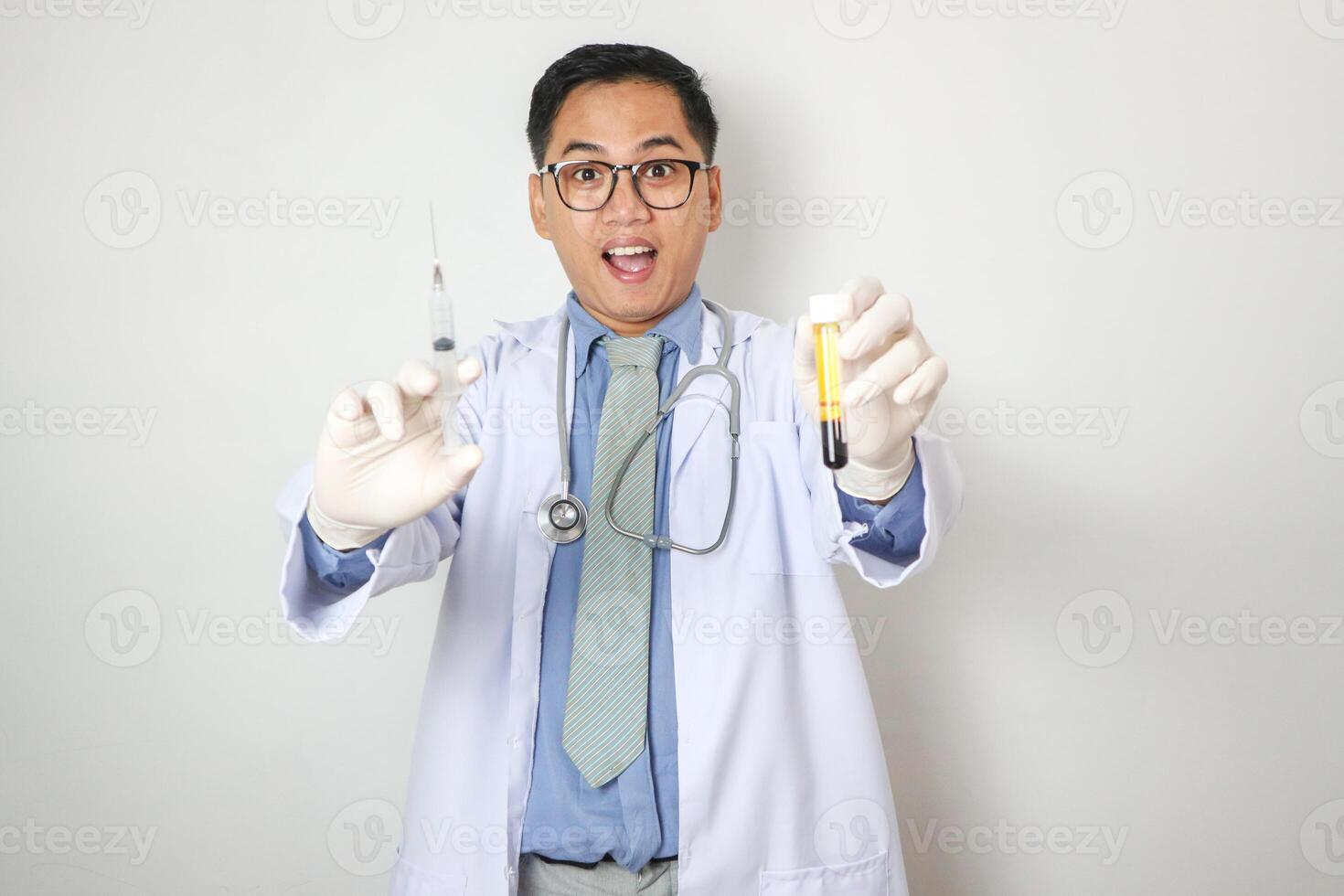 Portrait of an Asian male doctor in uniform on isolated background. He was holding a syringe with an injection photo